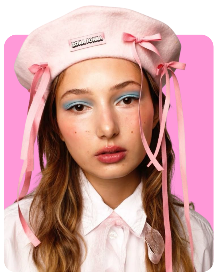 Photograph of young woman in pink hat with cascading ribbons.